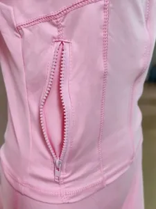 Gros plan d'une veste de yoga rose à séchage rapide avec poche zippée et coutures plates
