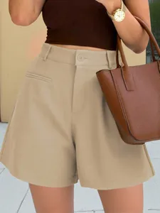 Close-up of high-waisted khaki A-line shorts with button closure and relaxed wide-leg fit