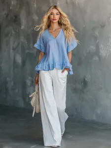 Detailansicht einer hellblauen V-Ausschnitt-Bluse mit Volants und weißer Hose.