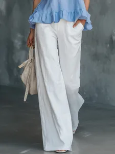 Detailansicht eines eleganten blauen Oberteils mit Rüschensaum und weißer Weithosenkombi