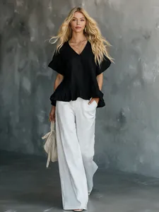 Detailansicht einer eleganten schwarzen V-Ausschnitt-Rüschenbluse mit weißer Hose