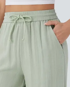 Macro detail view of sage green high-waisted drawstring linen pants with side pockets.