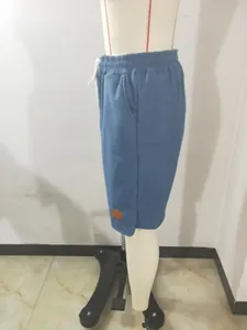 Vista lateral que muestra la textura y el parche de cuero de los shorts azules para hombre