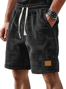 Gros plan sur un short à carreaux noir pour homme avec cordon crème et écusson en cuir
