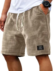 Detail of men's tan waffle-knit shorts featuring drawstring waist and classic style patch