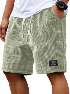 Detail view of men's sage green waffle knit shorts with drawstring and woven patch