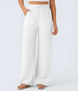 Detail of high-waisted white linen wide-leg pants with adjustable drawstring waist.
