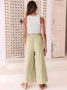 Back view of woman wearing casual light green wide-leg linen trousers and a white tank top