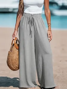 Detailed view of gray cotton linen wide-leg trousers with drawstring waist on beach