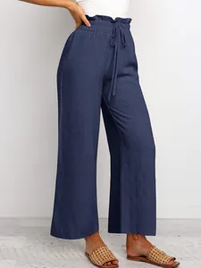 Detail of navy blue high-waisted wide leg trousers with elastic drawstring waistline.
