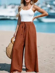 Women's brown linen wide leg trousers with drawstring waist shown on a beach model