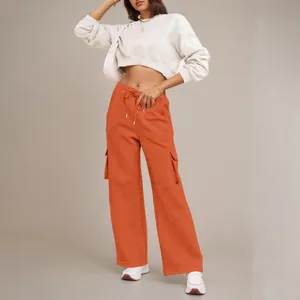 Detailweergave van de feloranje cargo-broek met trekkoord en grote zijzakken op een model.