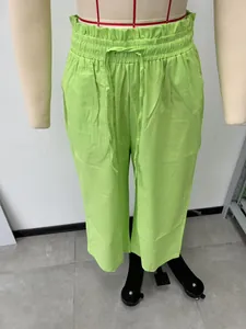 Detailed view of lime green high-waisted linen trousers with elastic drawstring waistband.