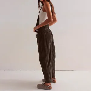 Vista lateral de mujer con peto de pana marrón, camiseta blanca y zuecos grises