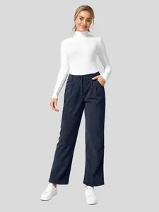 Vrouw draagt een marineblauwe corduroy broek met hoge taille en rechte pijpen op grijze basis