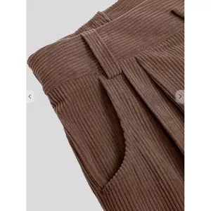 Detail van bruine corduroy broek met hoge taille en een getextureerde afwerking
