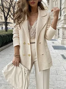 Nahaufnahme eines cremefarbenen strukturierten Blazers mit eleganten Goldknöpfen