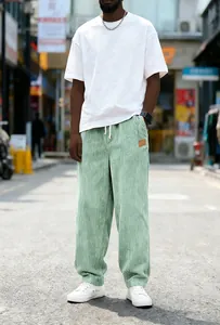 Full-length view of men's loose straight-leg corduroy pants in a pale mint green shade