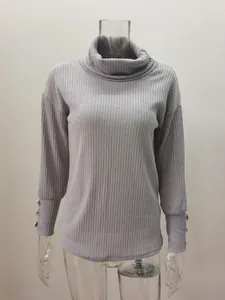 Pull en maille grise à col roulé avec boutons décoratifs aux poignets sur un mannequin.