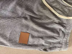 Close-up detail of grey corduroy fabric on men's drawstring pants with brown patch