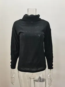 Détail d'un pull à col roulé noir côtelé pour femme avec des boutons dorés élégants aux poignets