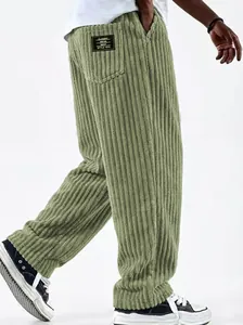 Macro detail of men's loose straight corduroy trousers in sage green with retro patch.