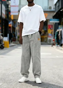 Full length detailed view of men's grey corduroy drawstring trousers in an urban street