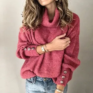 Détail d'un pull en maille rose à col montant avec boutons décoratifs aux poignets.