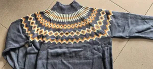 Close-up of gray knitted sweater featuring orange and white geometric jacquard pattern