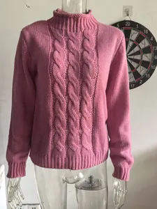 Close-up view of a pink high-neck cable knit sweater with chunky floral texture patterns