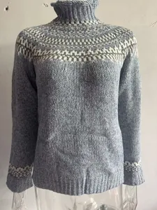 Detail view of blue chunky knit turtleneck sweater with Nordic jacquard pattern.