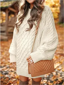 Detalle de un vestido de punto trenzado oversize crema en un cálido entorno otoñal