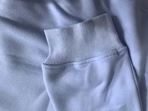 Vue macro montrant la texture du poignet bord-côte d'un sweat à capuche bleu clair.