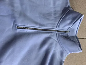 Détail de la fermeture éclair et du col d'un sweat-shirt bleu clair pour hommes.