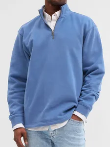 Detail shot of men's blue quarter-zip stand collar sweatshirt with layered white shirt