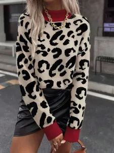 Detail view of a leopard print knit sweater with contrasting red ribbed collar and cuffs.