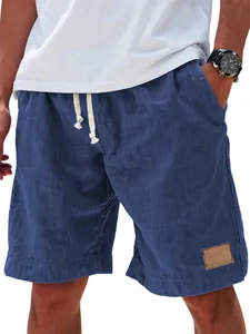 Gros plan d'un short bleu pour homme avec cordon, texture lin et détail d'écusson en cuir.