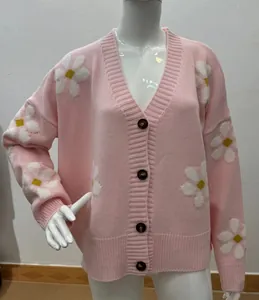 Vista dettagliata di un cardigan rosa in maglia con motivi a margherita su un manichino.