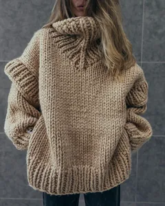 Detailed close-up of chunky knit pattern on a bulky camel-colored high-neck sweater