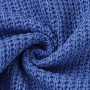 Close-up detail of soft blue chunky knit fabric on a women's high neck sweater.