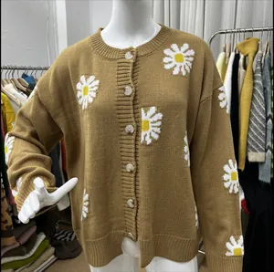 Detaillierte Makroansicht der weißen Gänseblümchen-Stickerei auf dieser braunen Strickjacke