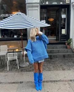 Street style shot of a woman in an oversized blue chunky knit turtleneck sweater