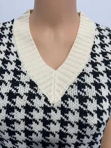 Detailaufnahme des V-Ausschnitts und des schwarz-weißen Hahnentrittmusters der Strickweste
