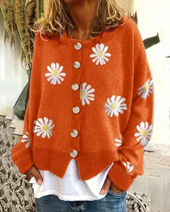 Detailansicht der orangefarbenen Strickjacke mit weißen Gänseblümchen-Stickereien.