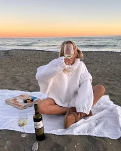 Detailed view of a cozy white chunky knit turtleneck sweater worn on a sunset beach
