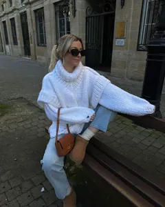 Detail of white oversized chunky knit turtleneck sweater in street style setting