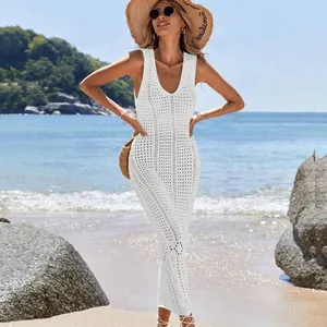 Detail of white sleeveless crochet maxi dress worn as beach cover-up on sandy shore