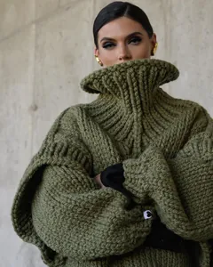 Macro view of olive green oversized chunky knit sweater with statement high neck collar