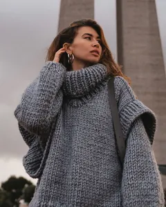 Close-up of oversized chunky knit grey turtleneck sweater with layered sleeve detail