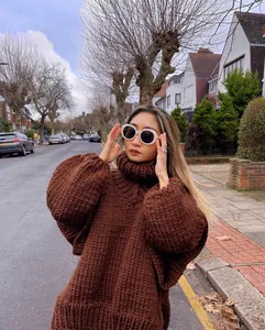 Woman wearing a chunky brown oversized turtleneck knit sweater in an outdoor street setting